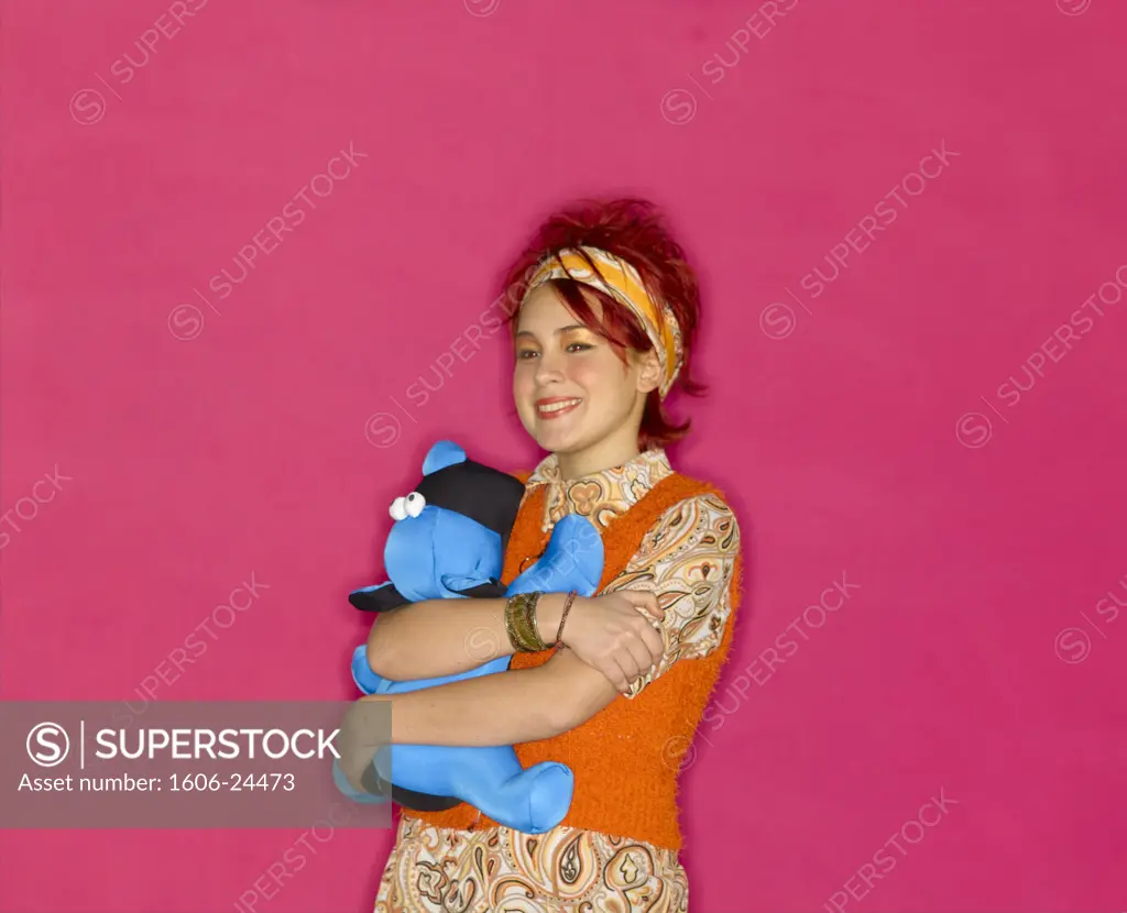 Young woman, headband and colourful clothes, pink background, clutching soft toy and holding powder puff
