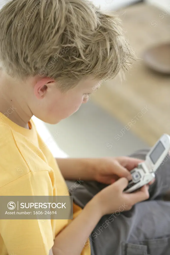 IN*Portrait Joshua de profil regardant clavier de son téléphone mobile, assis en intérieur
