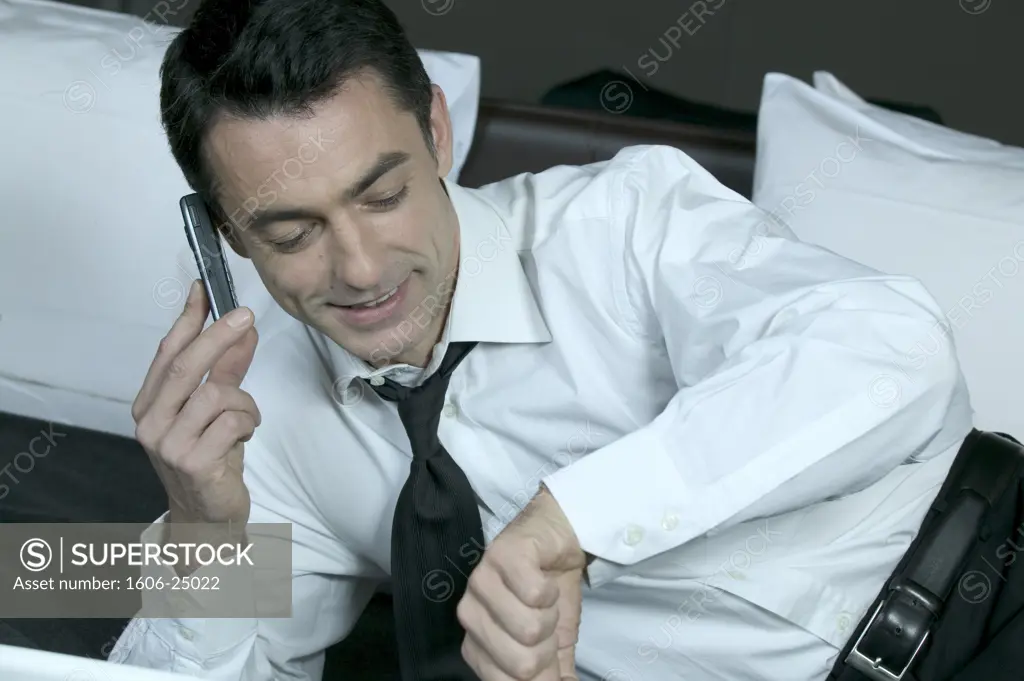 IN*Valery téléphonant allongé sur lit, chemise blanche, cravate noire