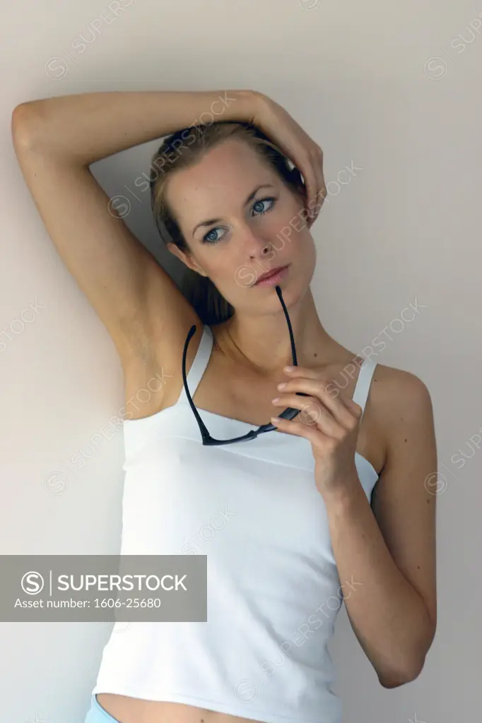 IN*Portrait Sophie pensive, main sur les cheveux, tenant lunettes de soleil, débardeur blanc