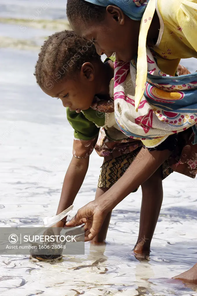 IN*Tanzanie, Zanzibar, Matemwe, deux fillettes jouant avec petit bateau sur l'eau