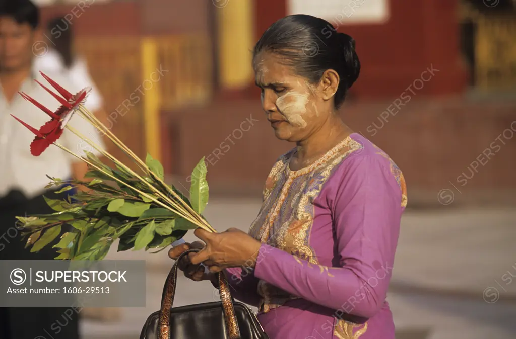 Burma, Rangoon, Shwedagon pagoda, young woman offering flowers, tanaka powder on face