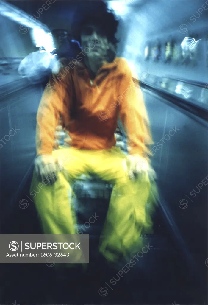 Man sitting on luggage on conveyor belt