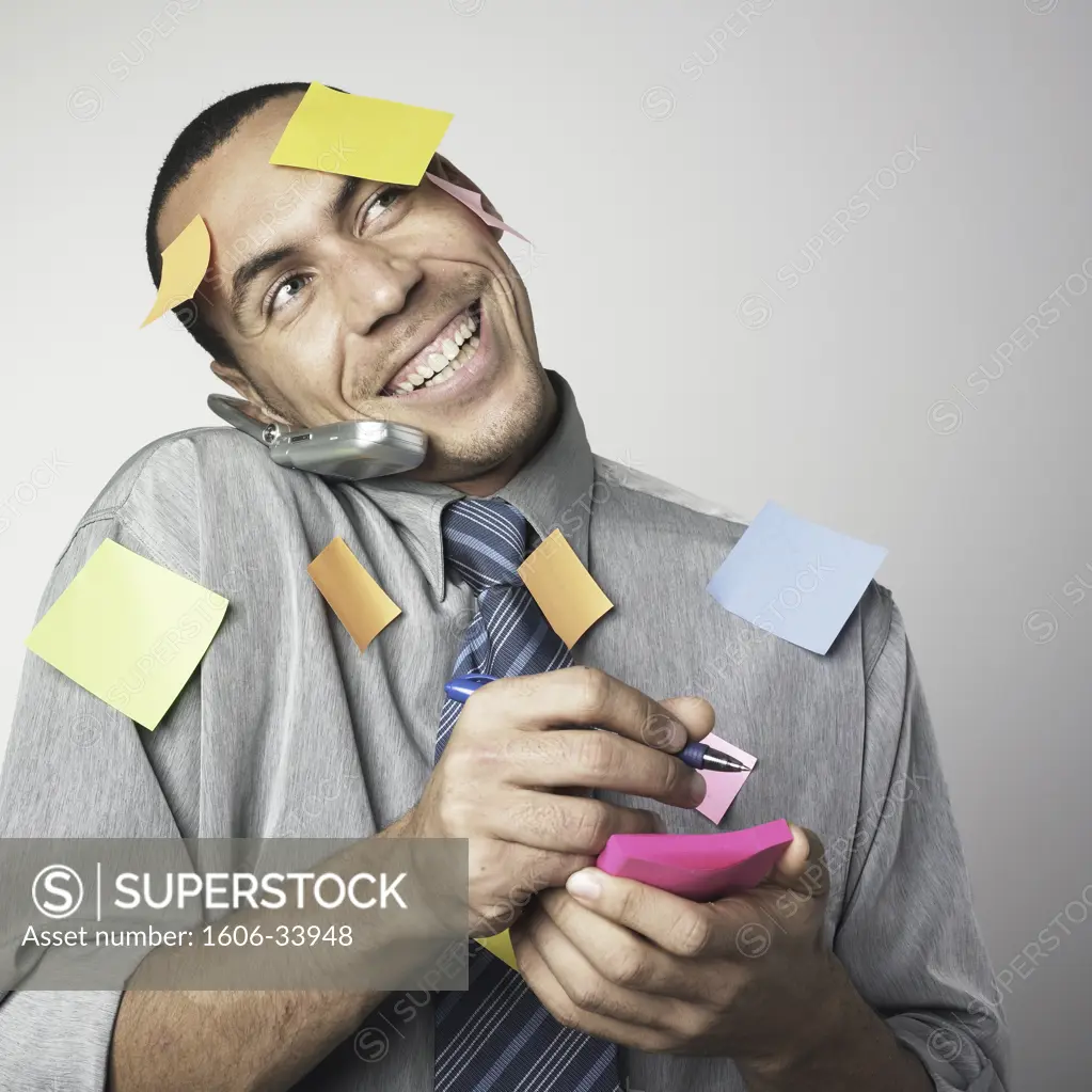 Portrait man smiling, on the phone, Post it on body and face, holding notepad and pen