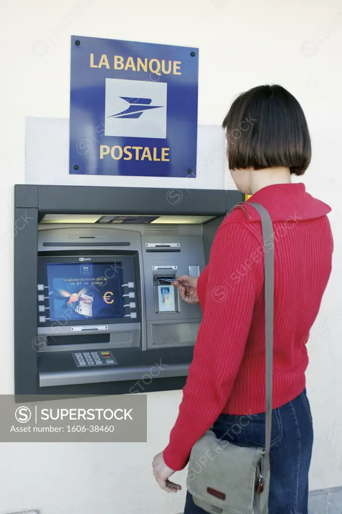 Woman putting her credit card in an ATM fo the bank "La Banque Postale"