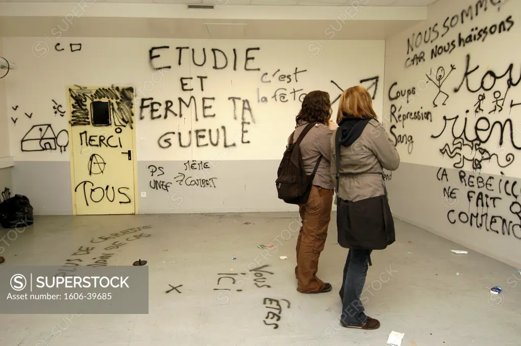 IN*44. Nantes, dégradation des locaux de la faculté de sociologie suite à leur occupation par des étudiants en lutte contre le CPE (contrat première embauche), tags et slogans sur les murs, 2 étudiantes de dos (04/2006)