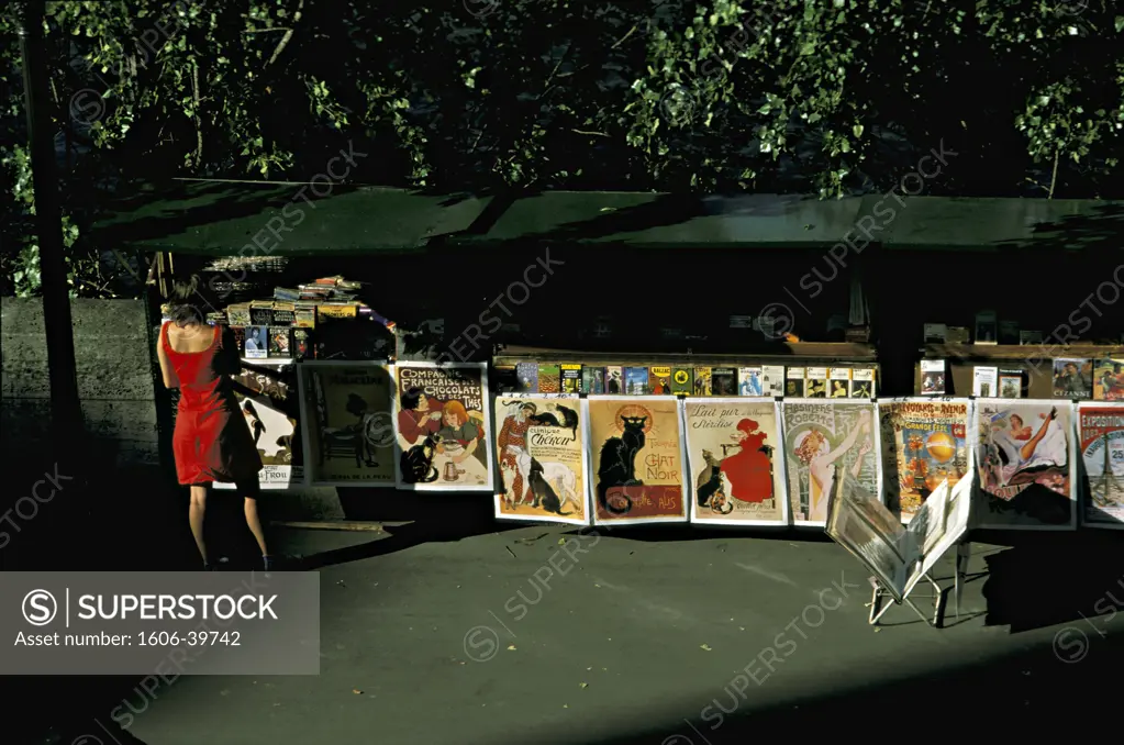 Paris, stand of a secondhand bookseller in the qay Voltaire, woman in red dress looking at posters
