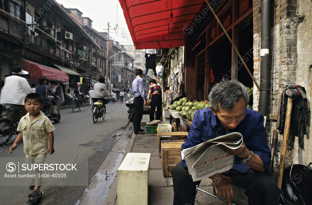 China, Shanghai traditionnal area, old man reading newspaper in the street