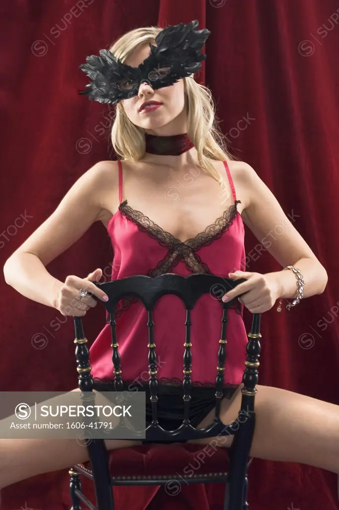 Young woman in underwear sitting on a chair, mask