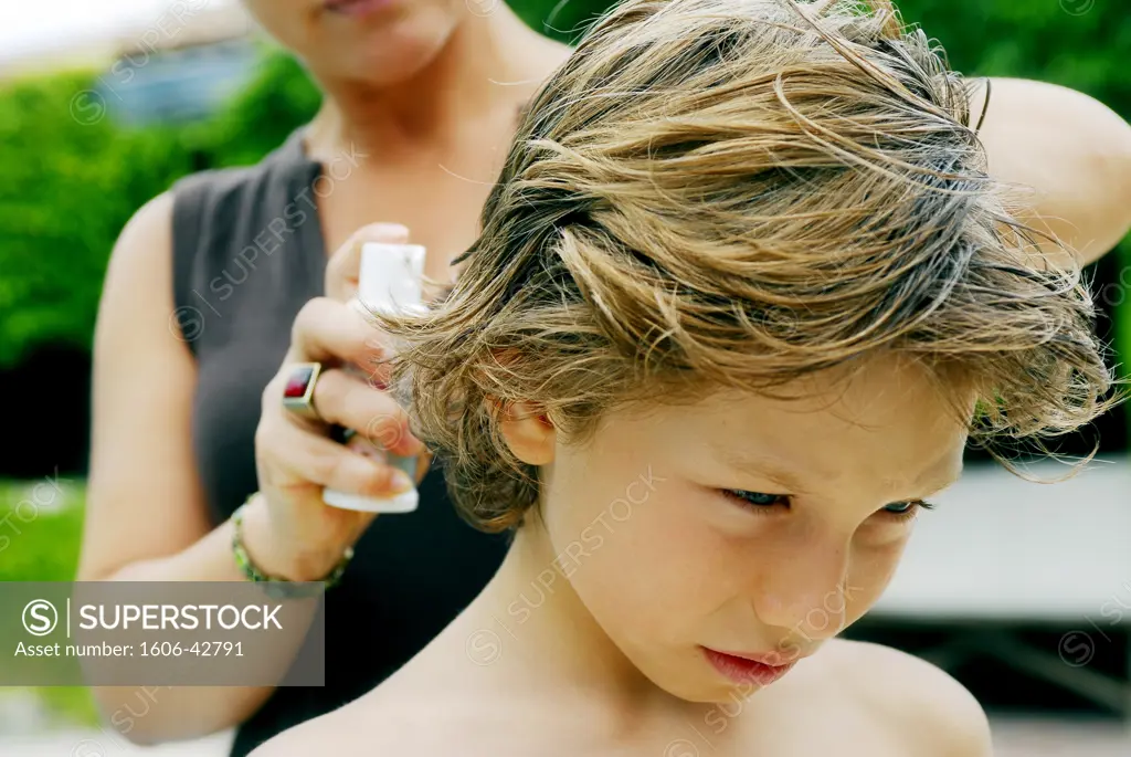 Mother putting anti-lice product on its son hair