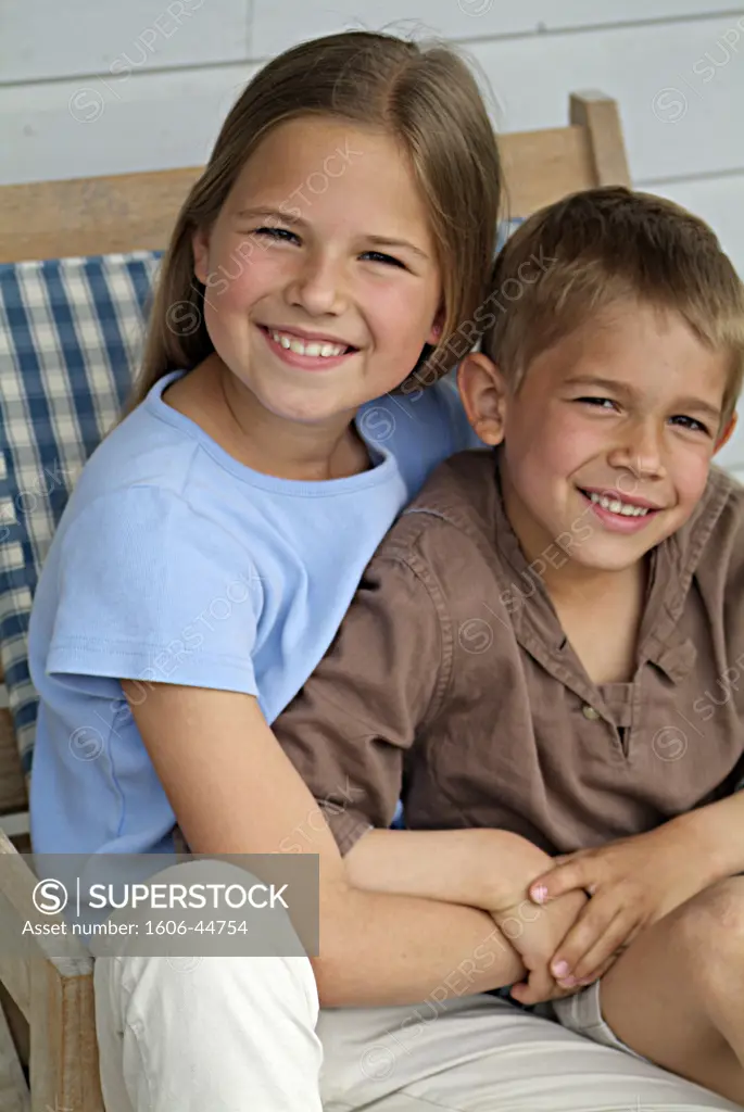 Two children sitting outdoors, smiling