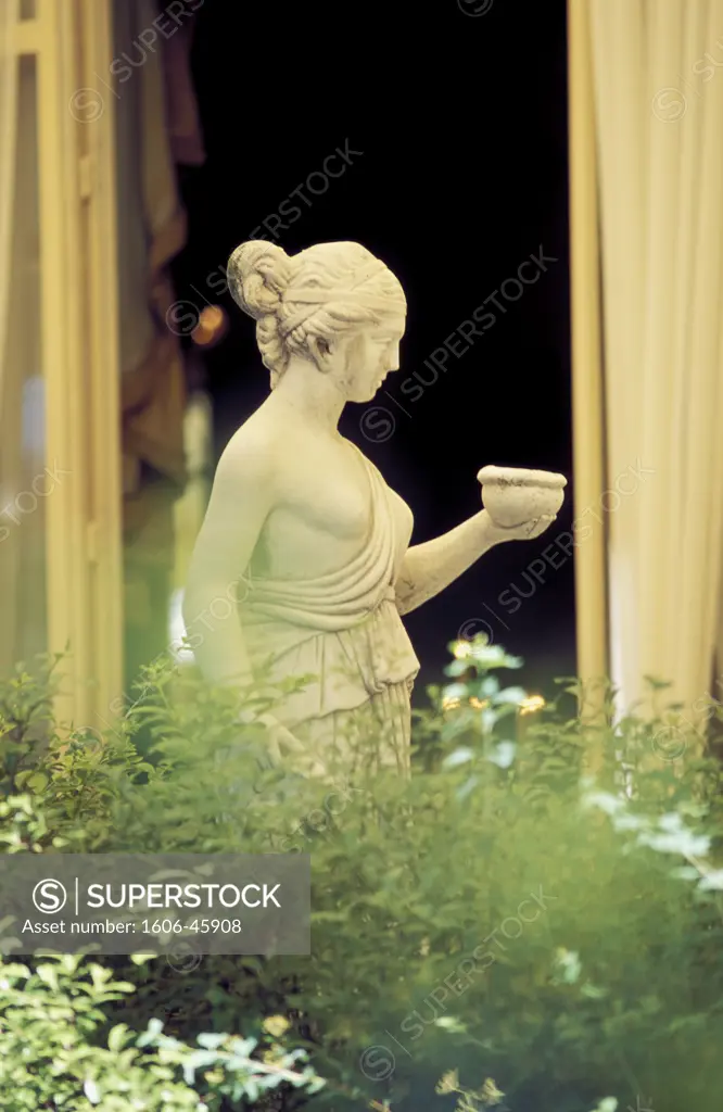 France, Paris, Ritz palace garden, statue of woman in front of a window, plants