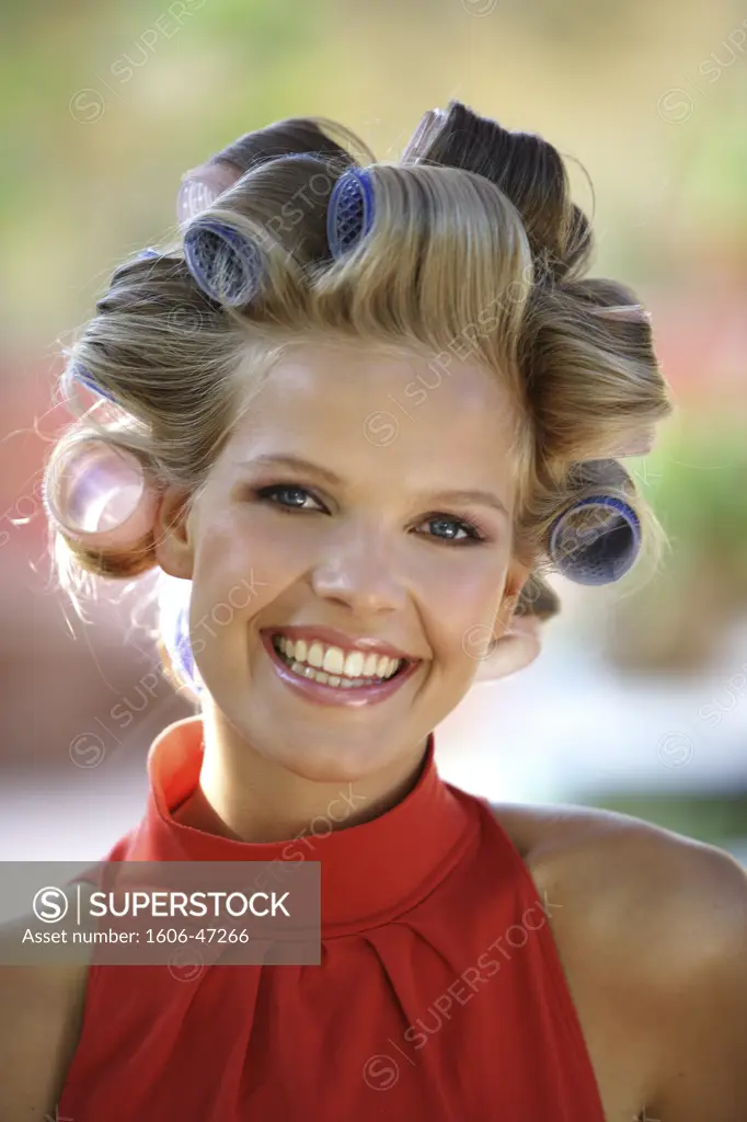 Portrait of Christina looking at the camera, smiling, curlers in her hair