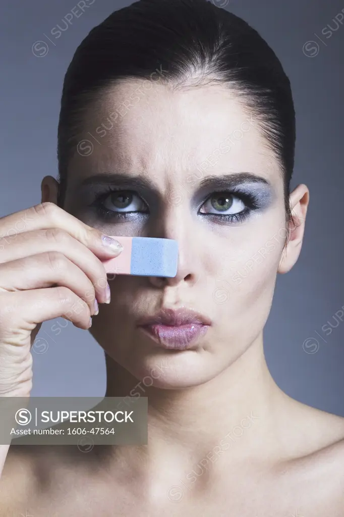 Portrait of a young woman touching her nose with eraser
