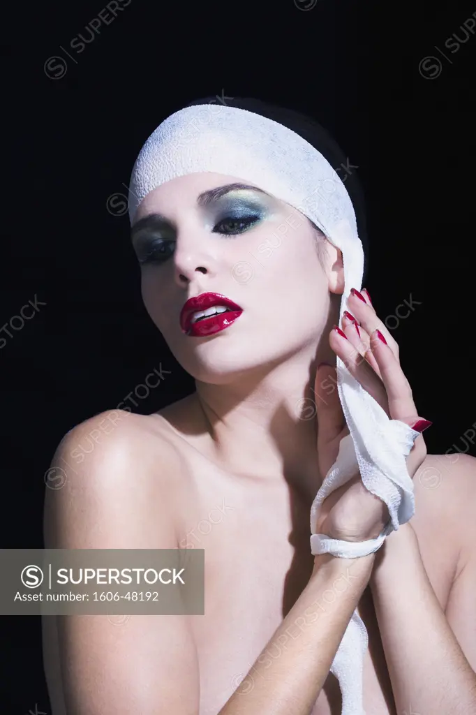 Naked woman removing bandages from her head