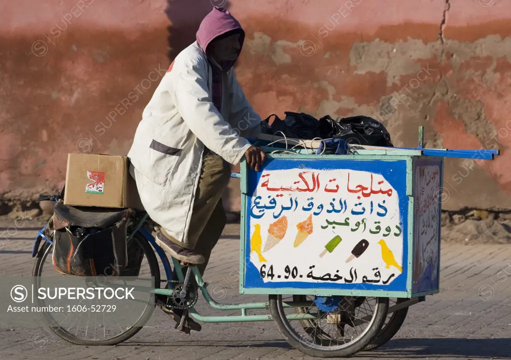 Morocco, Marrakech, ice-cream seller on delivery tricycle, in front of city wall