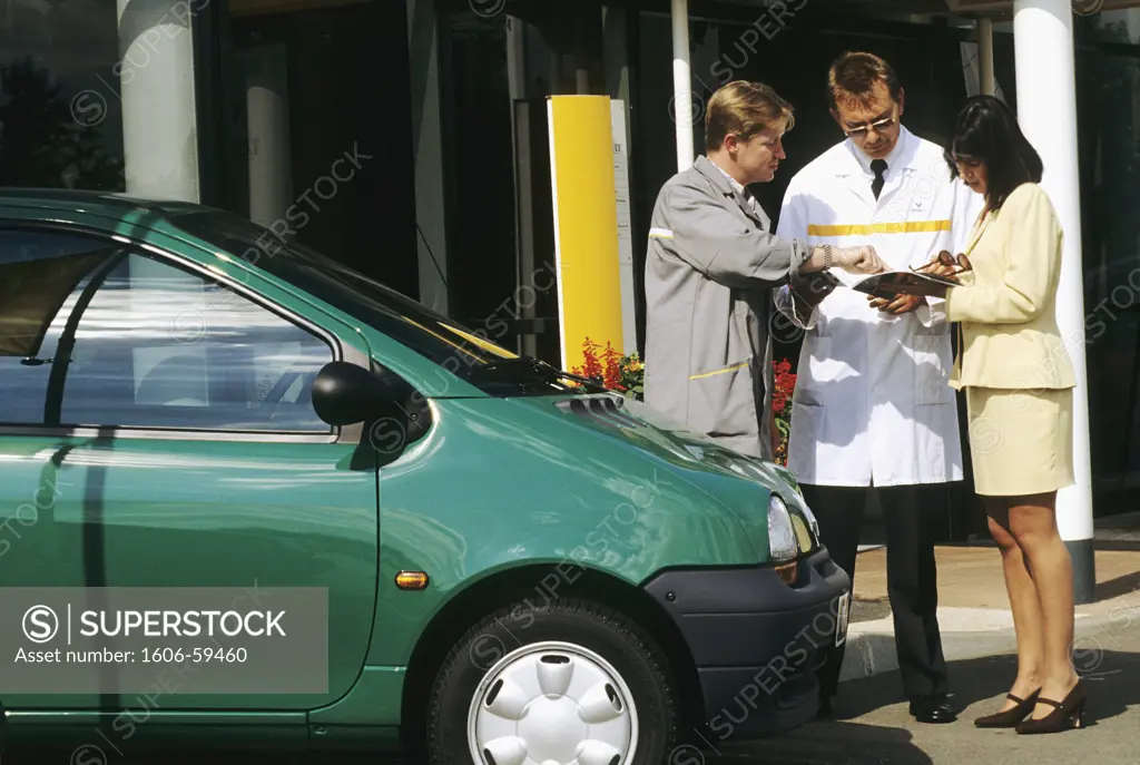 France, woman and two technicians talking in front of a car dealer