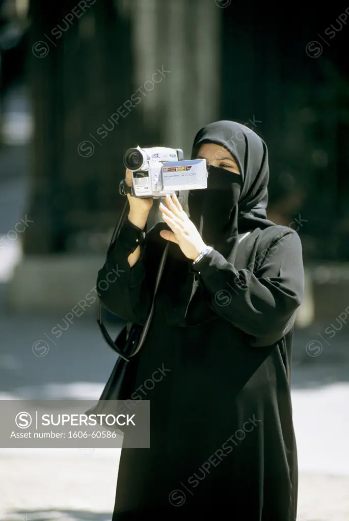 Woman wearing a veil using a camcorder