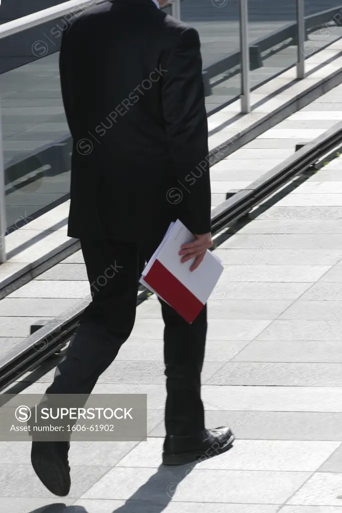 France, Ile-de-France, Hauts-de-Seine, La Défense, man walking, holding a file folder