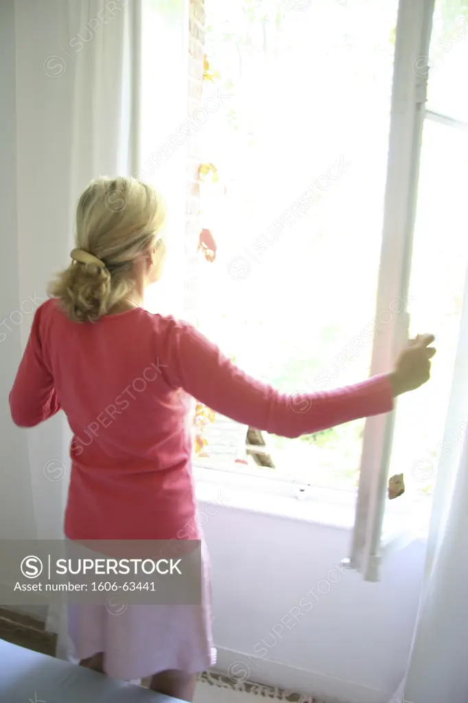 Backview of a woman opening a window