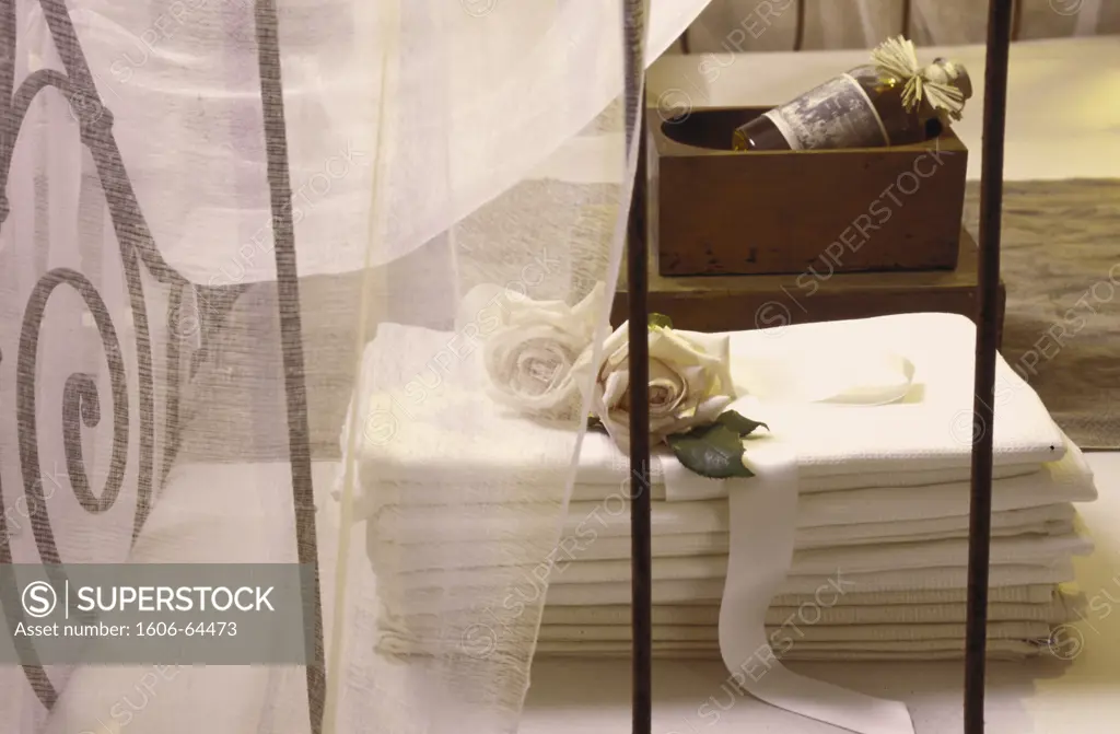 Serviettes en nid d'abeille posées sur un lit en fer avec une moustiquaire et deux roses blanches