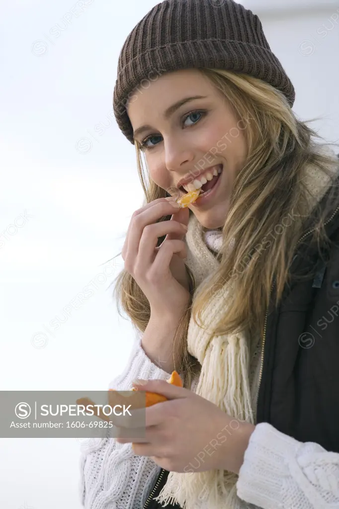 Teenage girl eating clementine, winter clothes