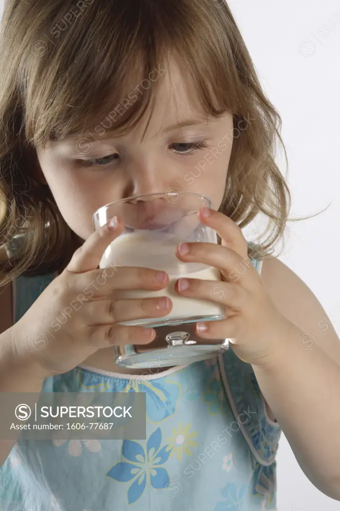 Little girl drinking glass of milk, studio