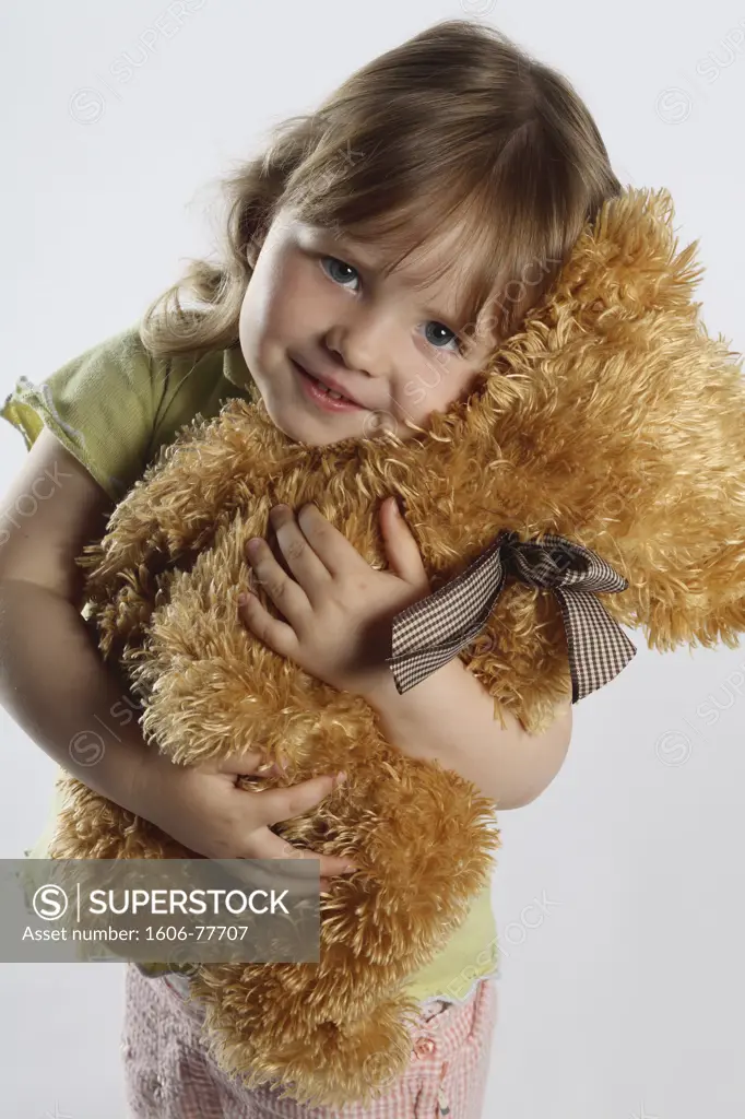 Little girl holding a teddy bear, studio