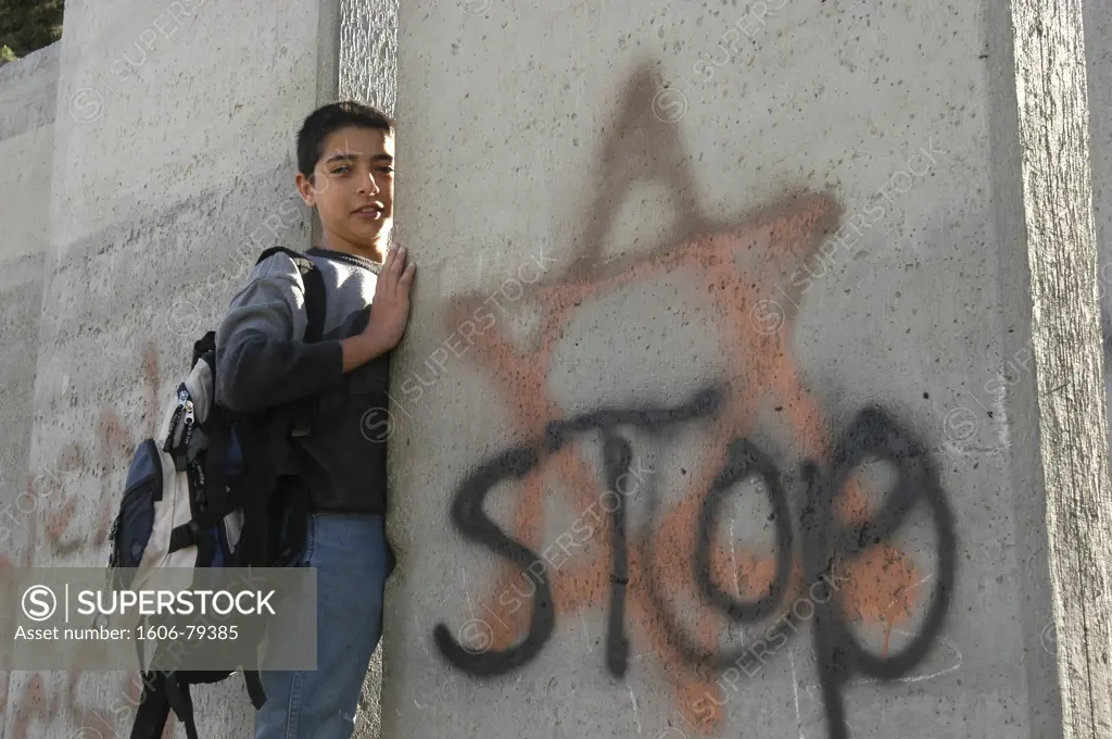 Israel, Jérusalem, Palestinian schoolboy climbing through the Israeli West Bank security barrier, in the village of Abu Dis