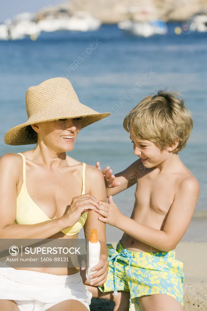 Boy applying sun lotion on woman's shoulder