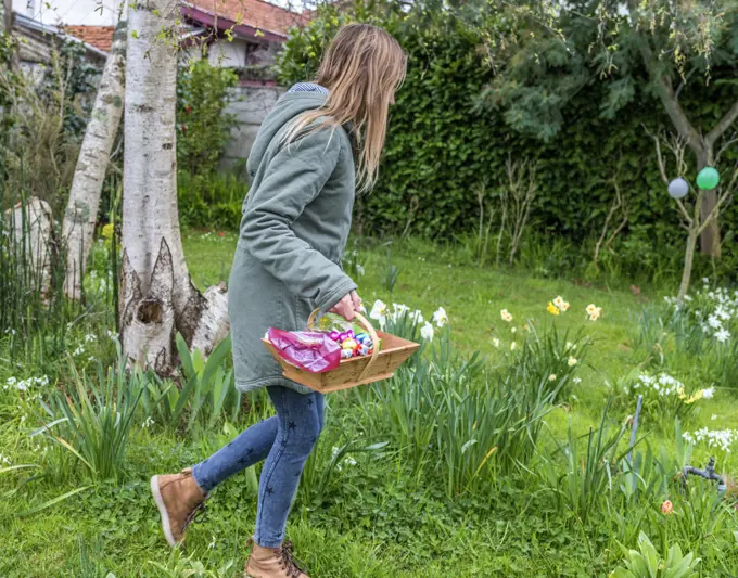 France, Easter, teenager hunting chocolate eggs in a garden.