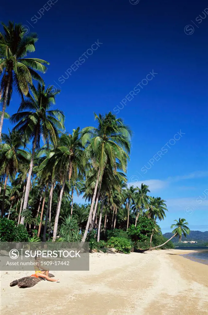 Philippines, Palawan, Bascuit Bay, El Nido, Girl Sunbathing on Tropical Beach