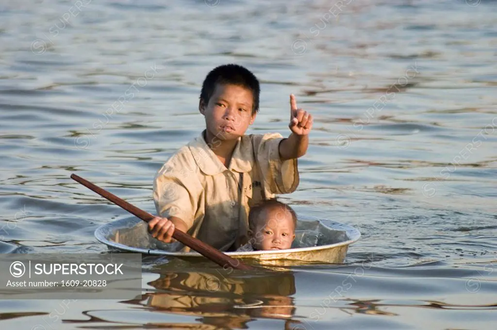Young Cambodian boy floating inside a washbasin on Tonle Sap River, Siem Reap, Cambodia