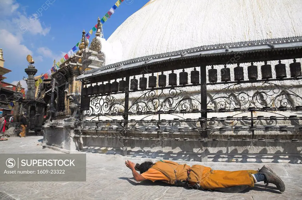 Nepal, Kathmandu, Swayambunath Stupa Monkey Temple Tibetan pilrim making full body prostrations round stupa