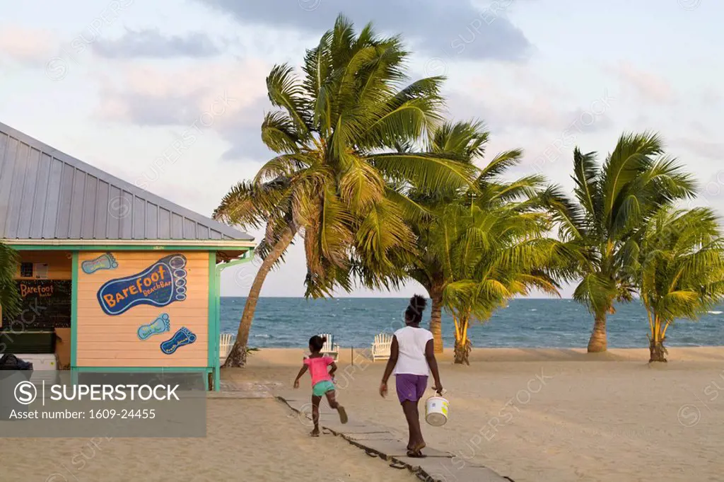 Belize, Placencia, Woman and daughter walking towards beach bar