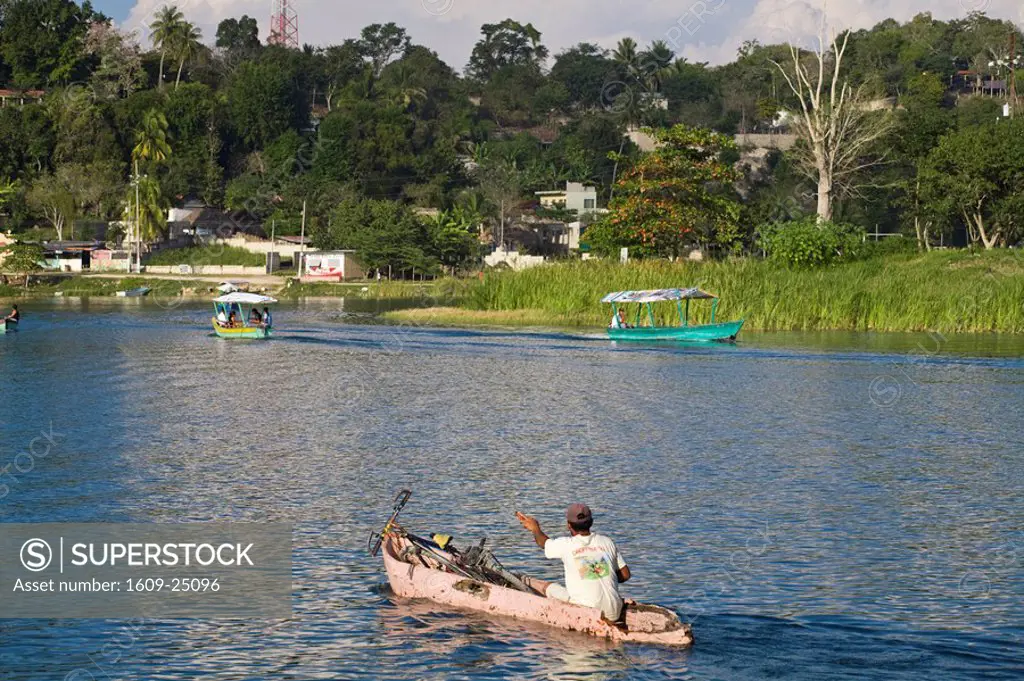 Guatemala, El Peten, Flores, Lago de Peten Itza, Man in dug_out canoe with bike