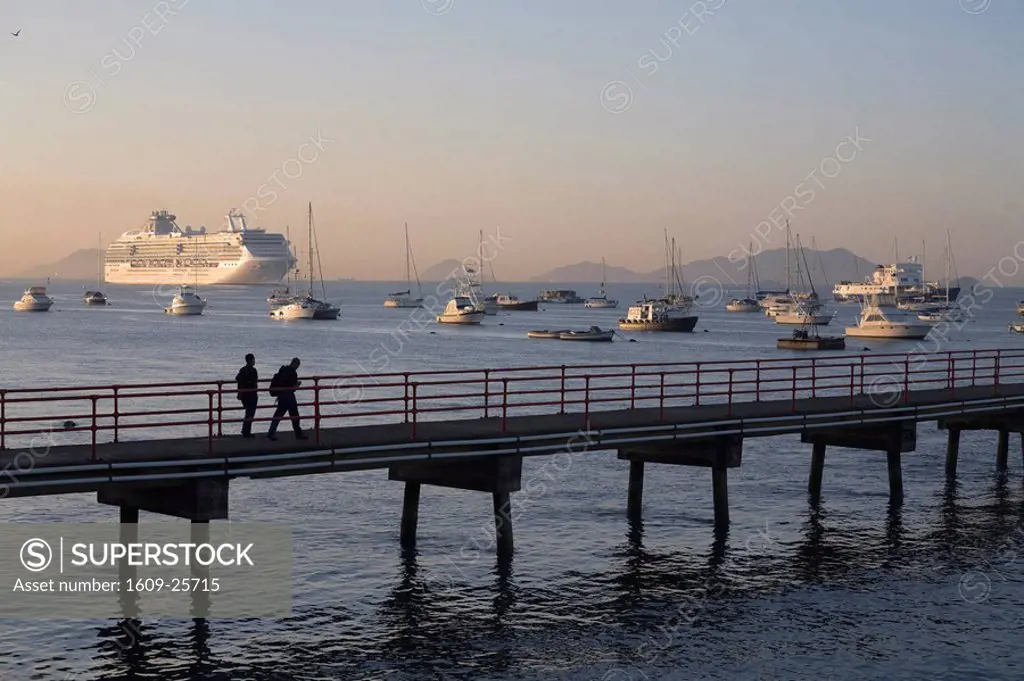 Panama, Panama City, People walking along jetty with a Cruise ship sailing in The Panama Canal