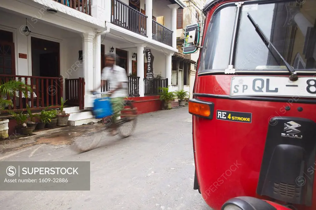 Man cycling past tuk tuk on Pedlar Street in Galle Fort, Galle, Sri Lanka