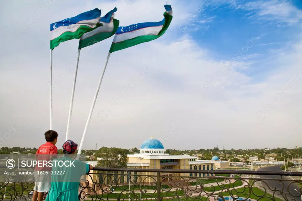 Uzbekistan, Tashkent, Mother and child standing under Uzbek flags looking at view of Tashkent from roof terrace