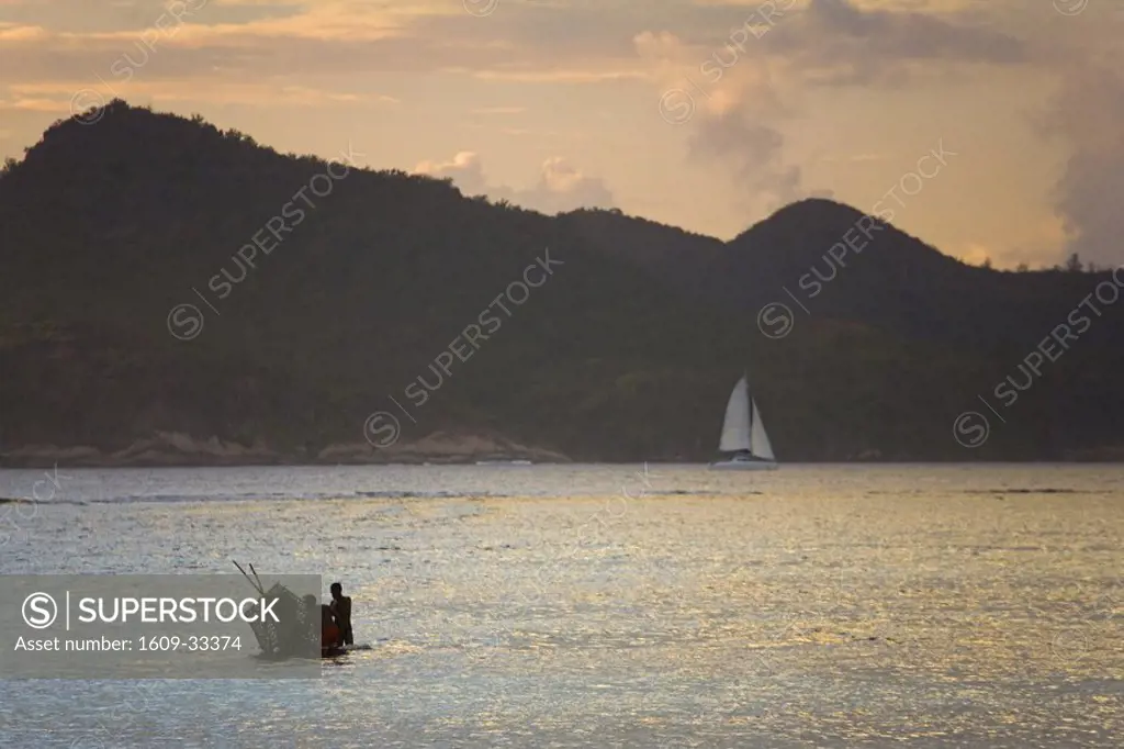 Fishermen at dusk with view of Praslin Island, La Digue Island, Seychelles