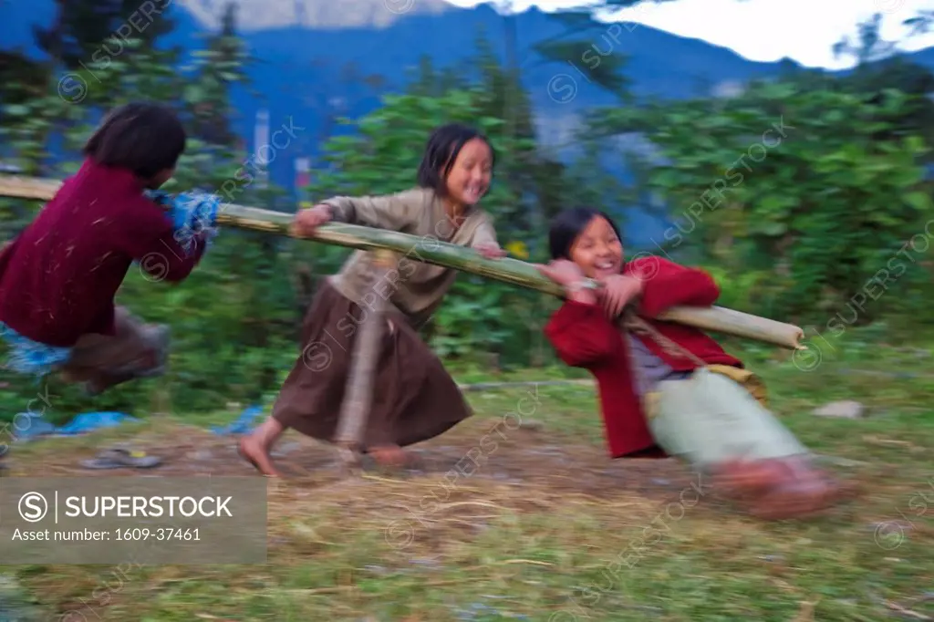 India, Sikkim, Khecheopalri Lake, Children playing on bamboo roundabout