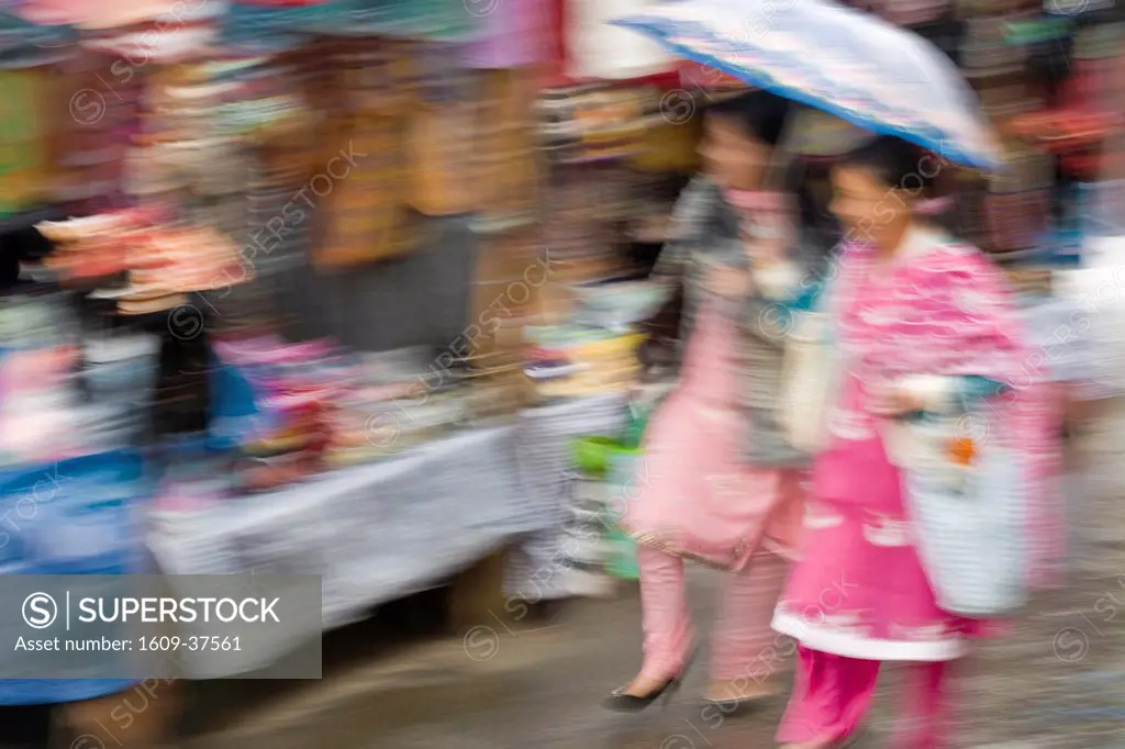 India, West Bengal, Darjeeling, Women holding umbrella walking through market