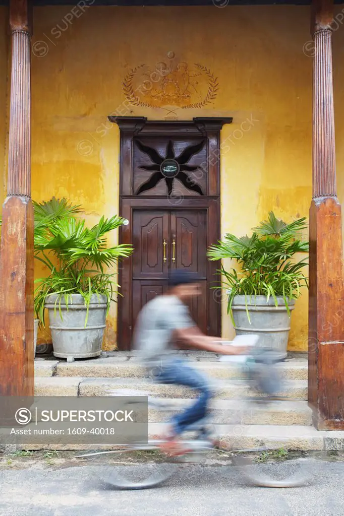 Man cycling past doorway in Old Town of Galle Fort, Galle, Sri Lanka