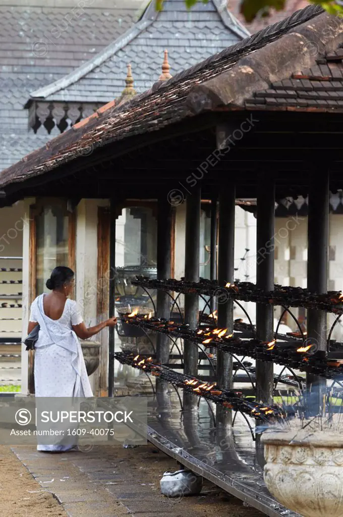 Woman lighting candles in prayer in Temple of the Tooth Sri Dalada Maligawa, Kandy, Sri Lanka