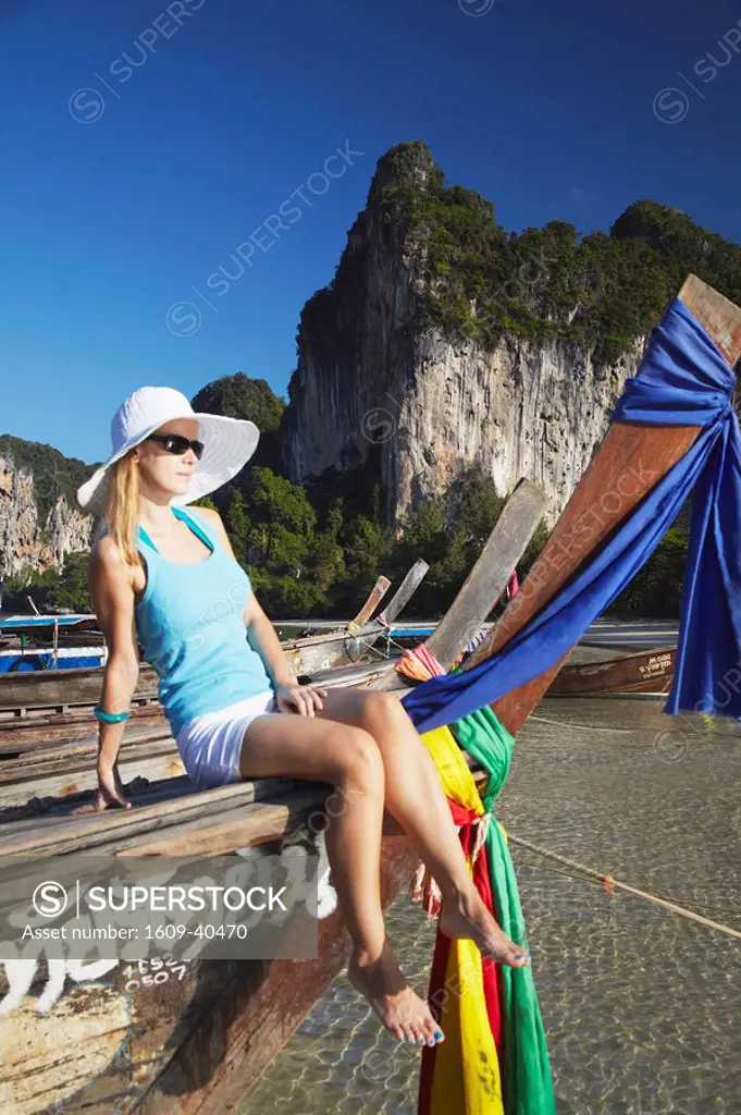 Woman sitting on long tail boat on Hat Rai Leh West beach, Railay, Krabi Province, Thailand MR