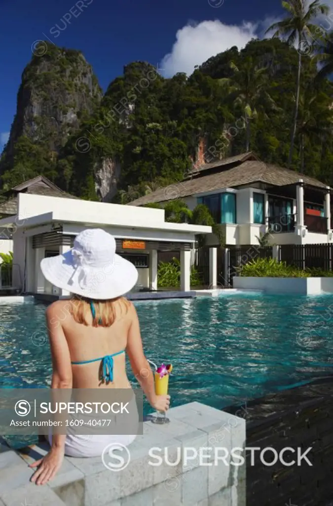 Woman relaxing by pool with drink in Bhu Nga Thani Resort and Spa, Railay, Krabi Province, Thailand MR