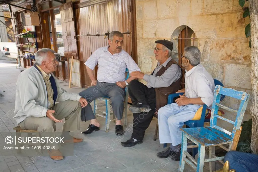 Turkey, Eastern Turkey, Gaziantep, Shoe cleaner and men sitting outside shop