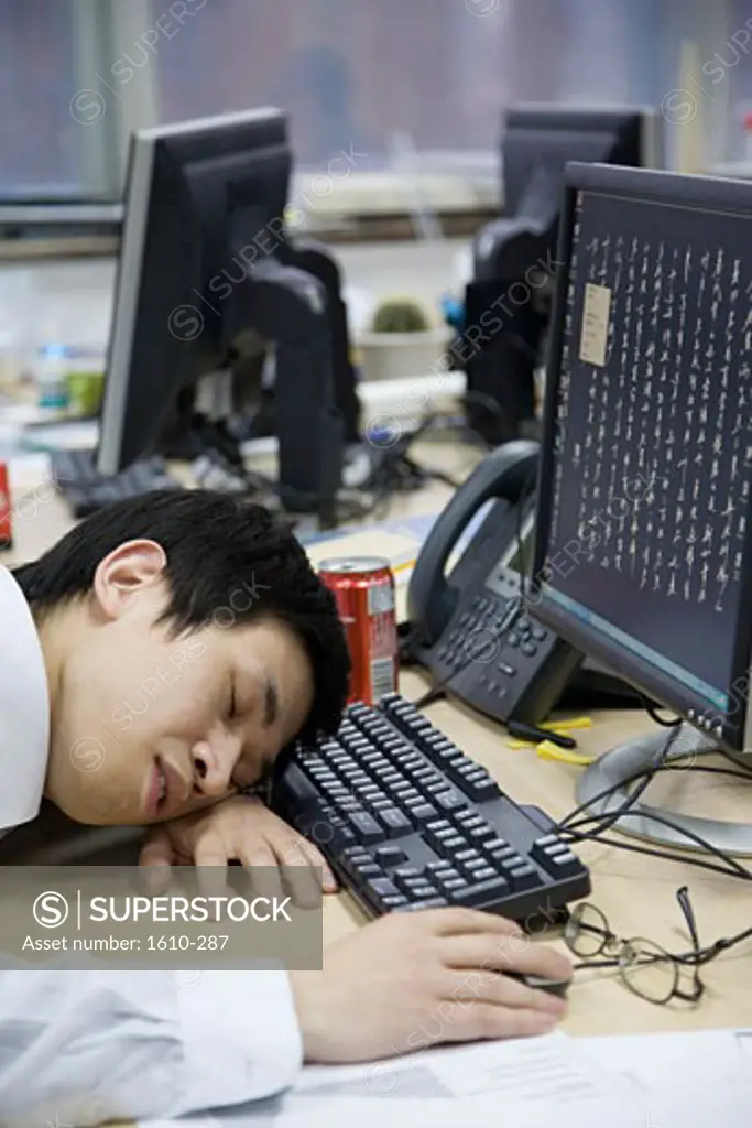 Close-up of a businessman sleeping in front of a computer