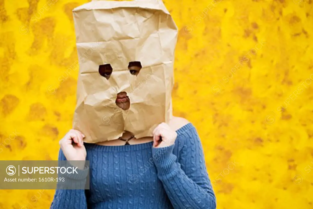 Close-up of a young woman covering her face with a paper bag