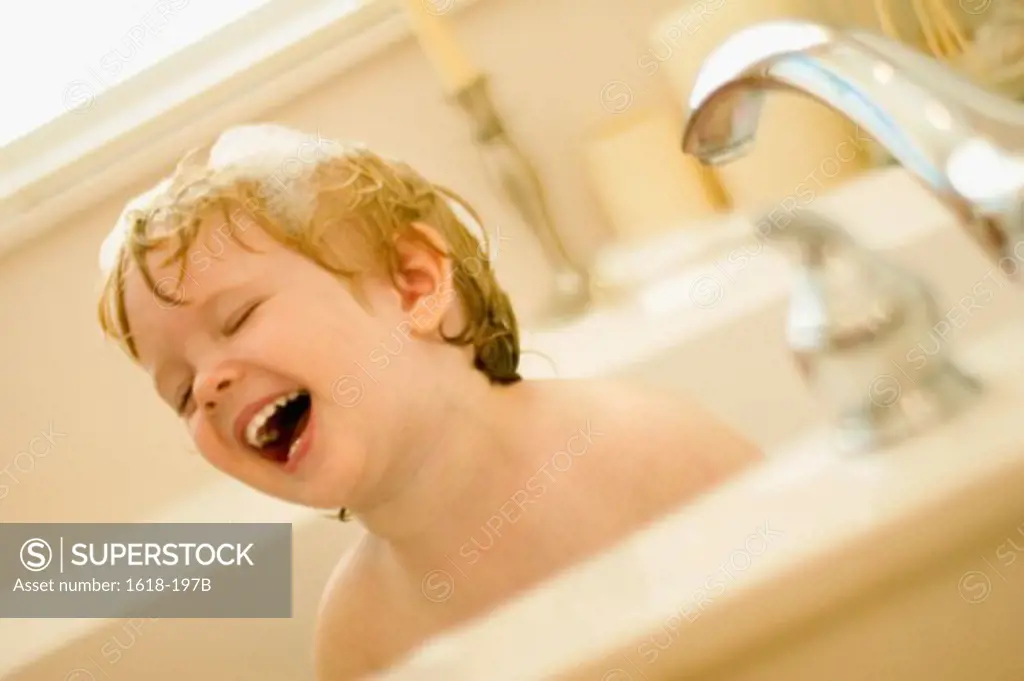 Close-up of a boy laughing in a bathtub